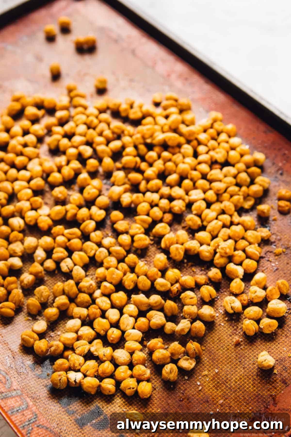 Oven-roasted chickpeas spread evenly on a baking sheet lined with parchment paper.
