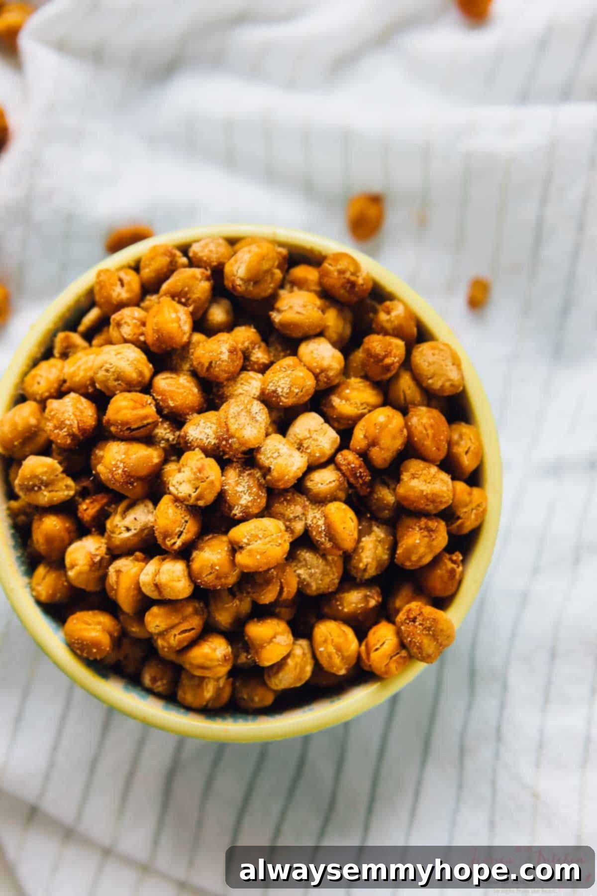 Overhead view of a white bowl overflowing with perfectly roasted, golden-brown chickpeas.