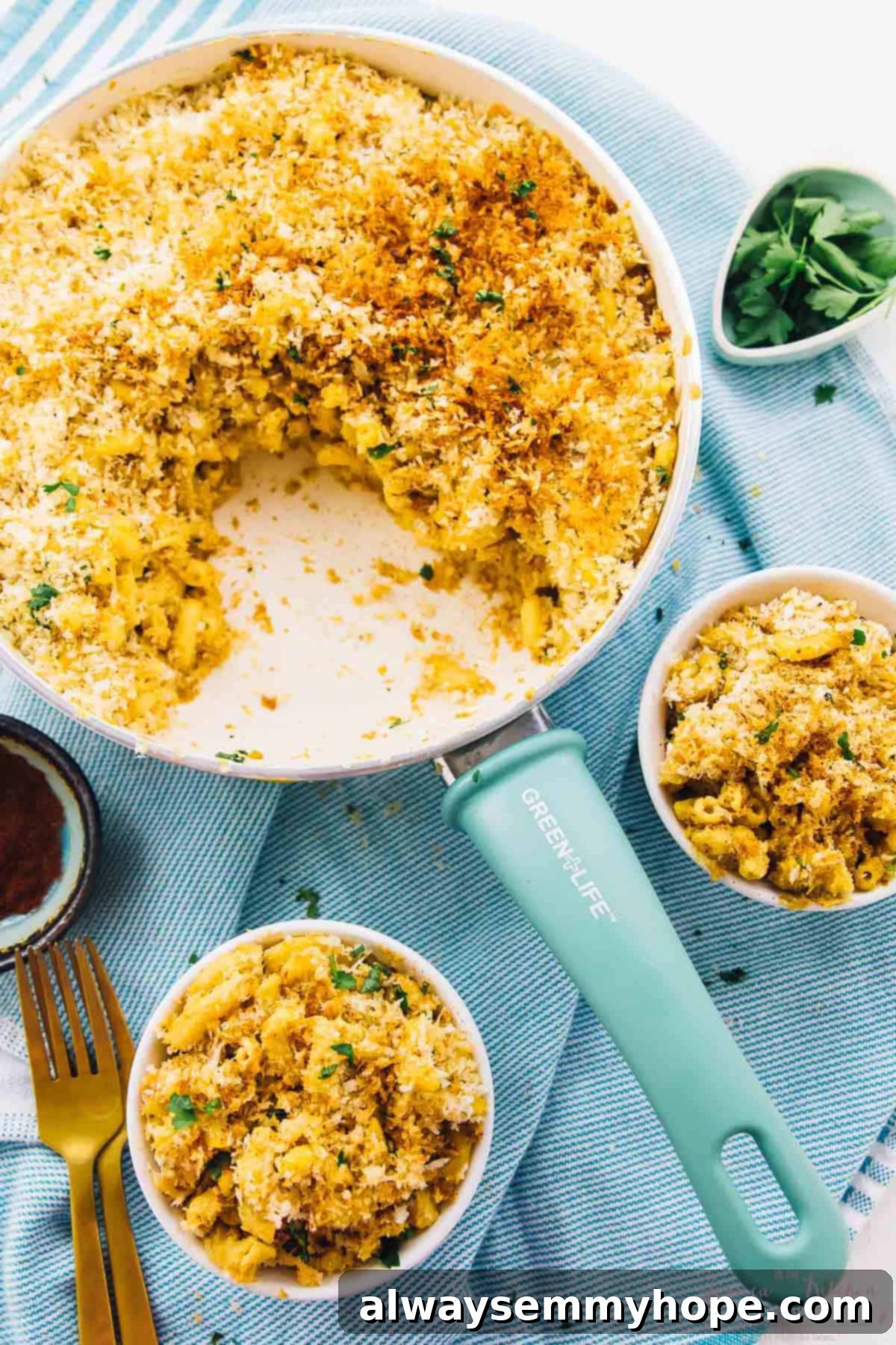 Overhead shot of creamy baked vegan mac and cheese in a skillet and two bowls.
