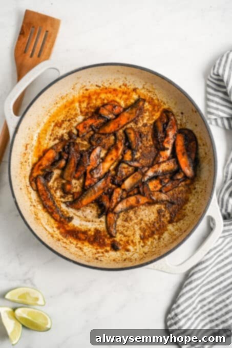 Meaty portobello mushrooms make the best vegan fajitas, sautéed with tender bell peppers and homemade fajita seasoning. Ready in 30 minutes! Seasoned portobello mushroom slices in a pan.