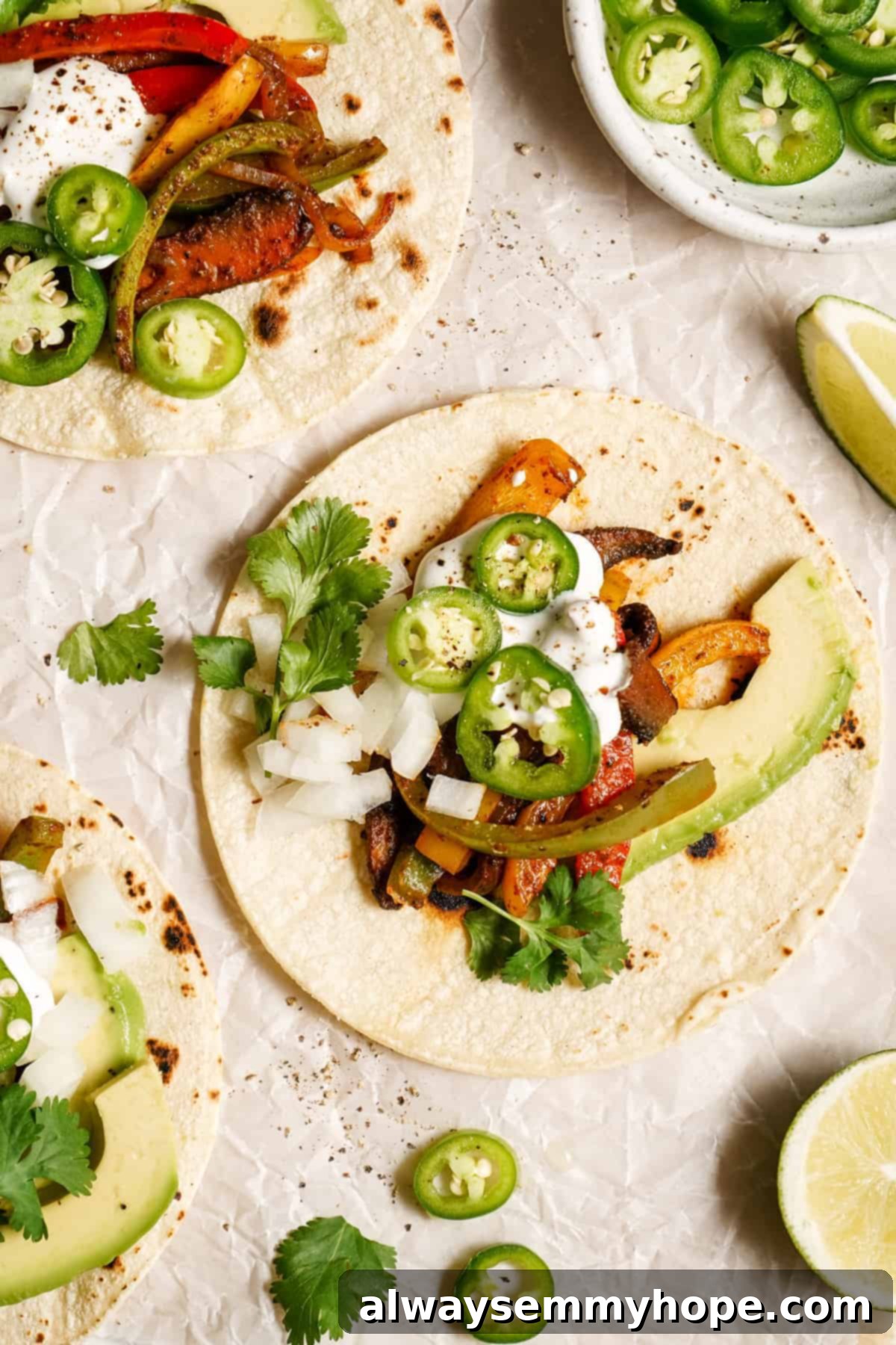 Meaty portobello mushrooms make the best vegan fajitas, sautéed with tender bell peppers and homemade fajita seasoning. Ready in 30 minutes! A vegan fajita with portobello mushrooms and jalapeno slices.