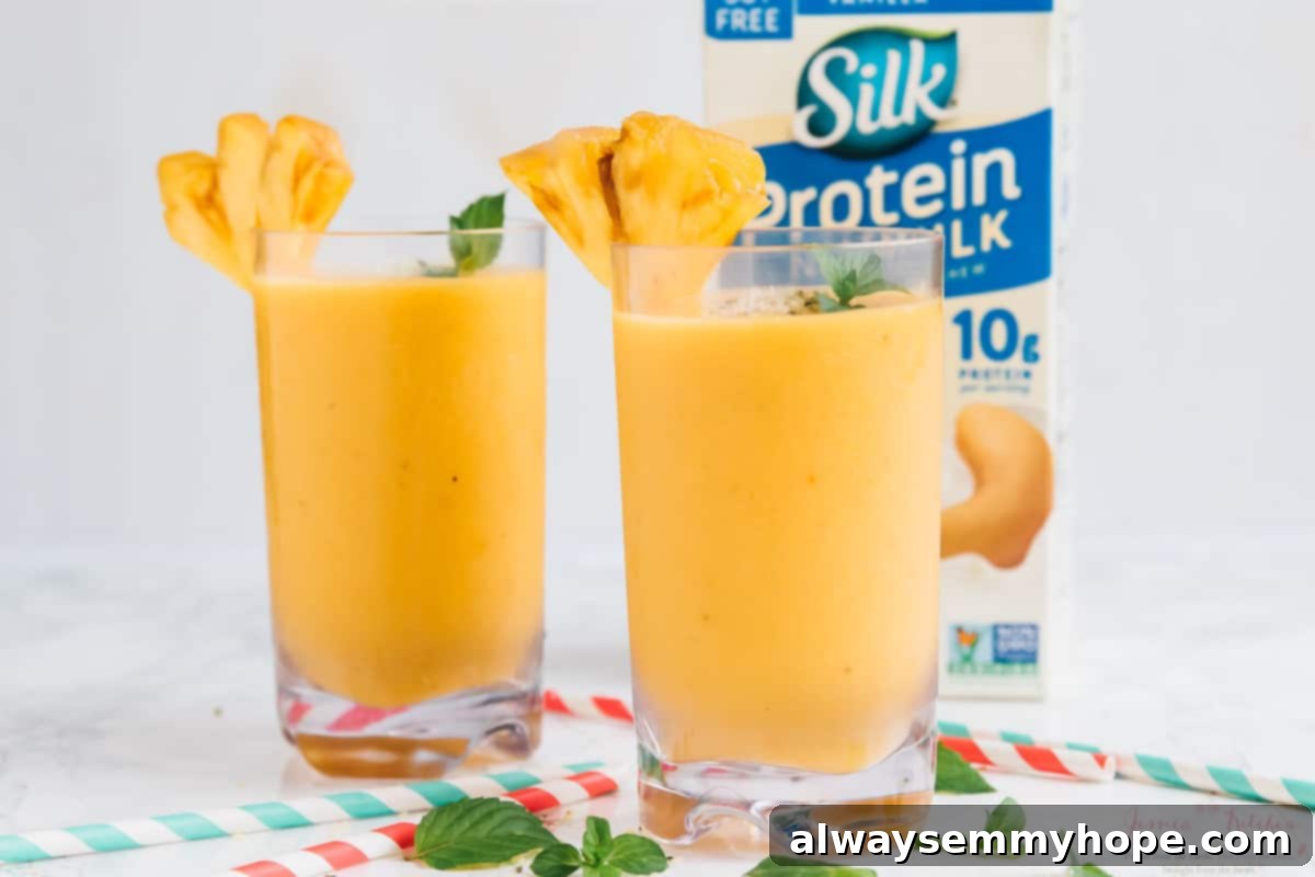 Sunshine Pineapple Peach Smoothie 6 Two glasses of pineapple peach smoothies are arranged next to a carton of Silk Protein Nutmilk, highlighting the key ingredient.