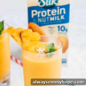 Sunshine Pineapple Peach Smoothie 9 Side shot of a smoothie in a glass with a carton of nut milk in the background.