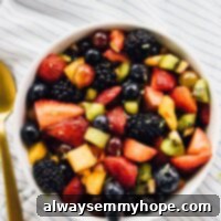 Vibrant Fruit Medley with Zesty Maple-Lime Drizzle 10 Top down view of a vibrant fruit salad in a white bowl with a golden spoon resting on the side, highlighting the fresh, colorful ingredients.