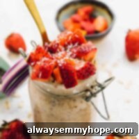 Tropical Strawberry Coconut Overnight Oats 2 Overnight oats in a glass jar with a gold spoon in it.
