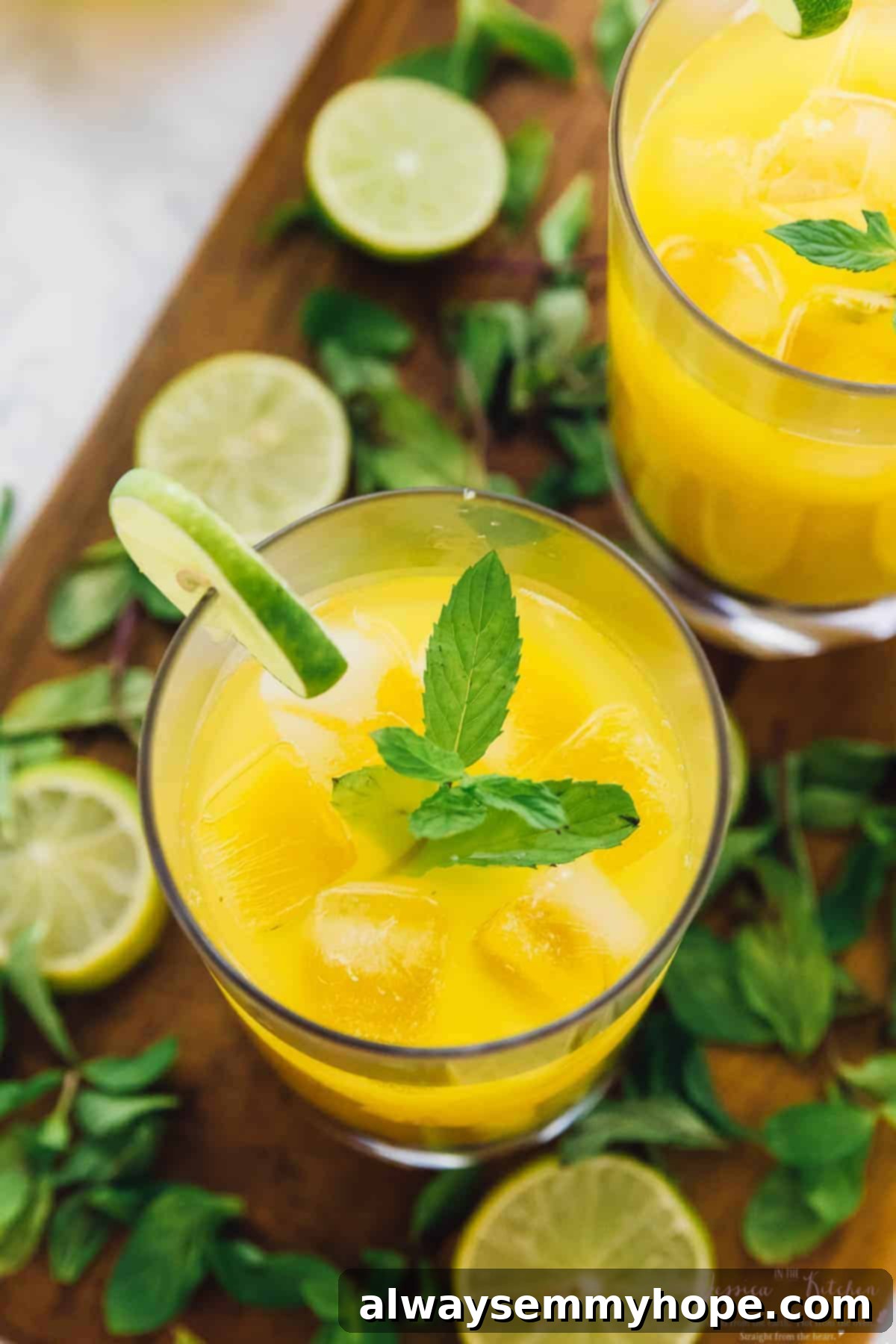 Top-down view of a mango mojito in a glass with ice, garnished with fresh mint and a lime wheel on the rim.