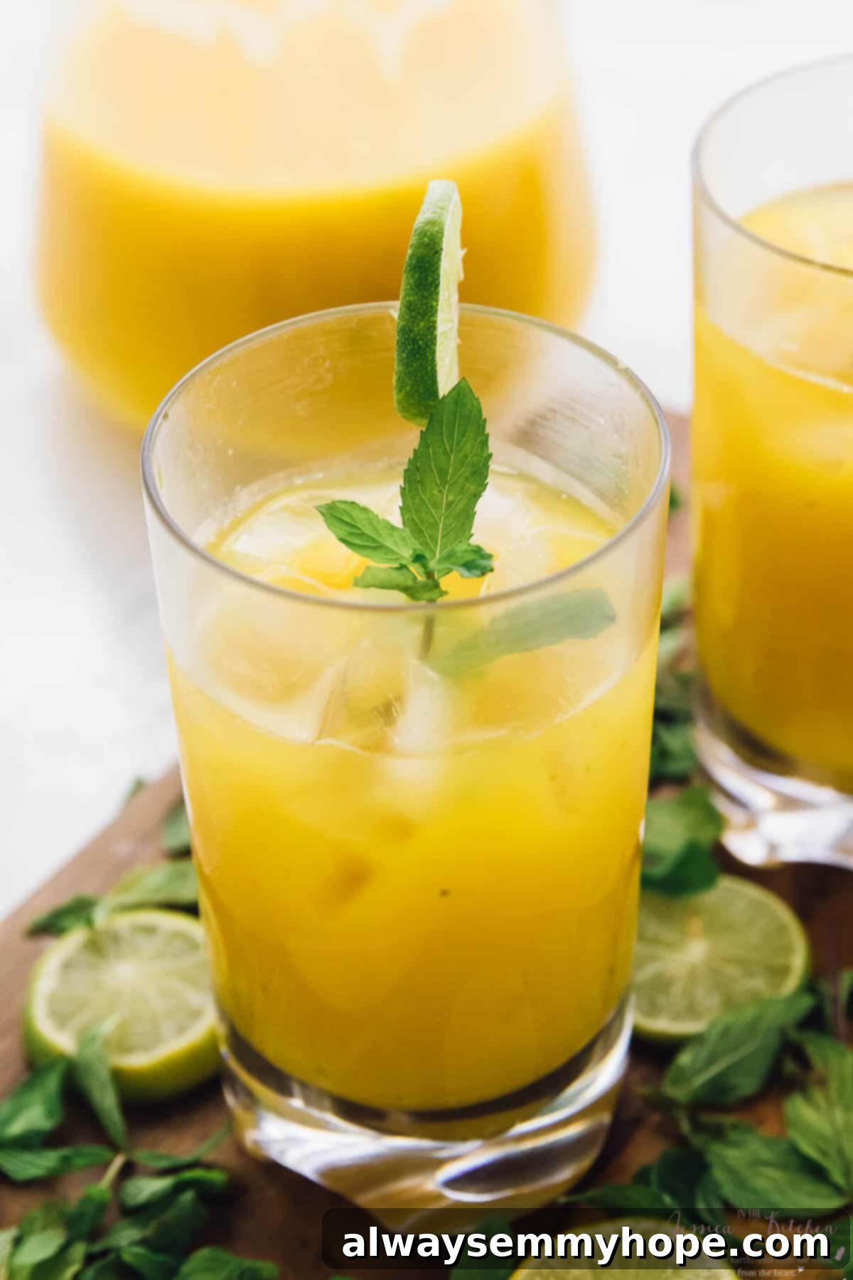 A single mango mojito in a tall glass, garnished elegantly with mint leaves and a lime slice on the rim, set against a blurred background.