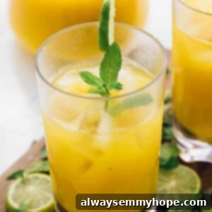 A mango mojito in a glass, garnished with mint and lime.