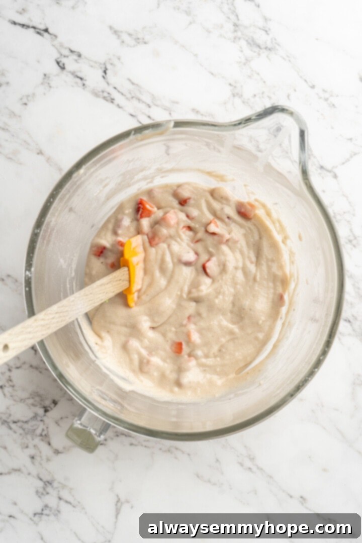 Overhead view of strawberry banana bread batter in a bowl after strawberries have been folded in.