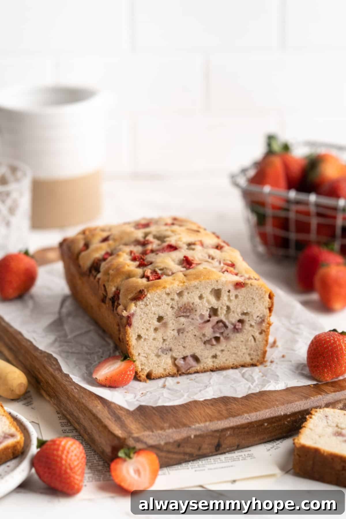 A freshly baked gluten-free vegan strawberry banana bread loaf with one slice removed, highlighting its moist and berry-filled texture.