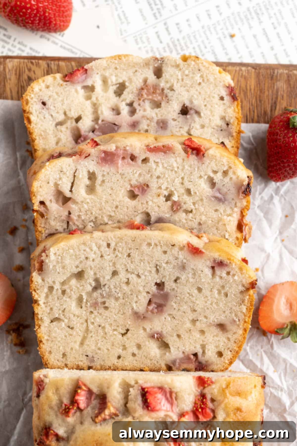 Overhead view of a freshly baked and sliced loaf of strawberry banana bread, showcasing the golden crust and berry-filled interior.