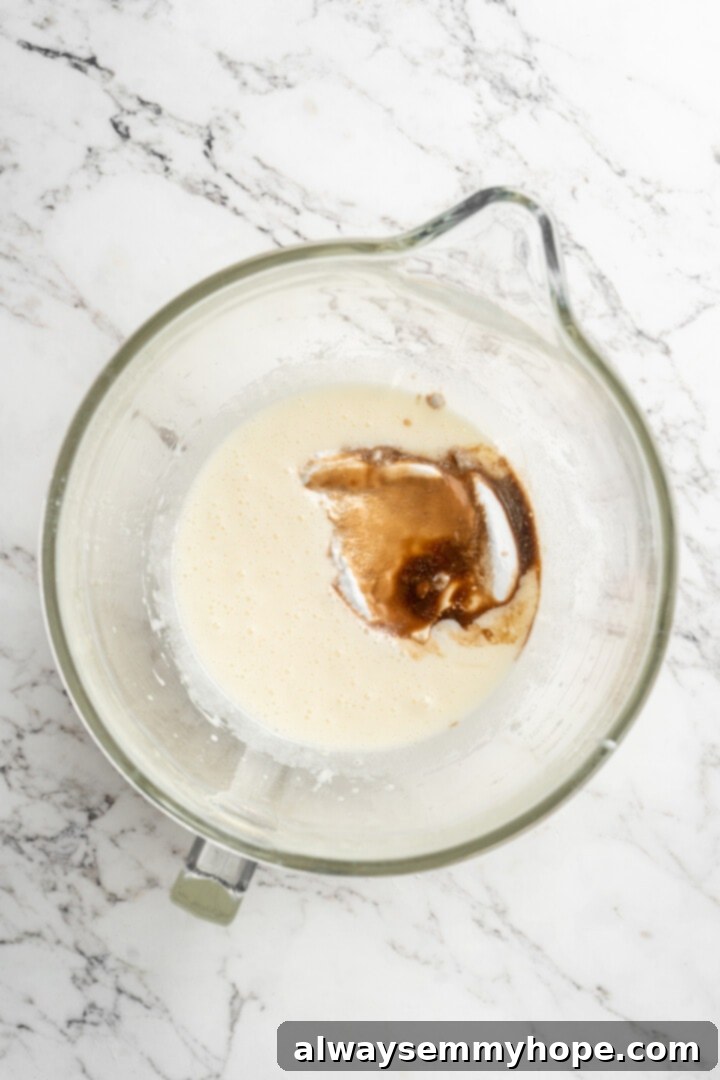 Overhead view of vanilla and vegan yogurt being added to the wet ingredients in a bowl.