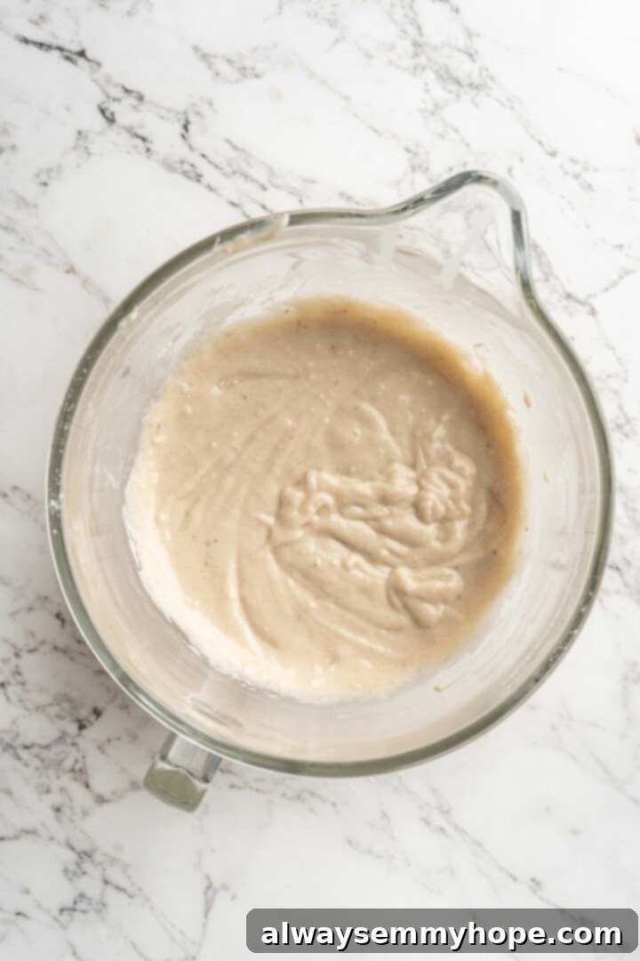 Overhead view of the fully mixed banana bread batter in a glass bowl, ready for additions.