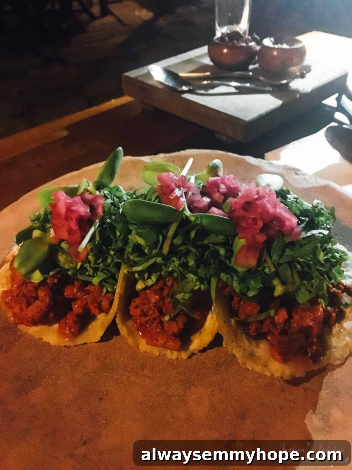 Tulum's Best Eats and Essential City Guide 13 Three tacos with pickle garnish on a wooden table.