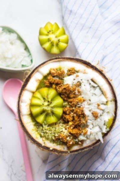 Seven Day Smoothie Reset Win A Prize 5 Overhead view of a beautiful coconut kiwi green smoothie bowl on a stylish striped cloth, artfully garnished with fresh fruit, inviting a healthy and visually appealing start to the day.