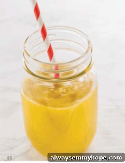 Seven Day Smoothie Reset Win A Prize 9 A bright orange mango turmeric smoothie in a stylish glass mason jar with a red straw, symbolizing health, tropical flavor, and anti-inflammatory benefits.