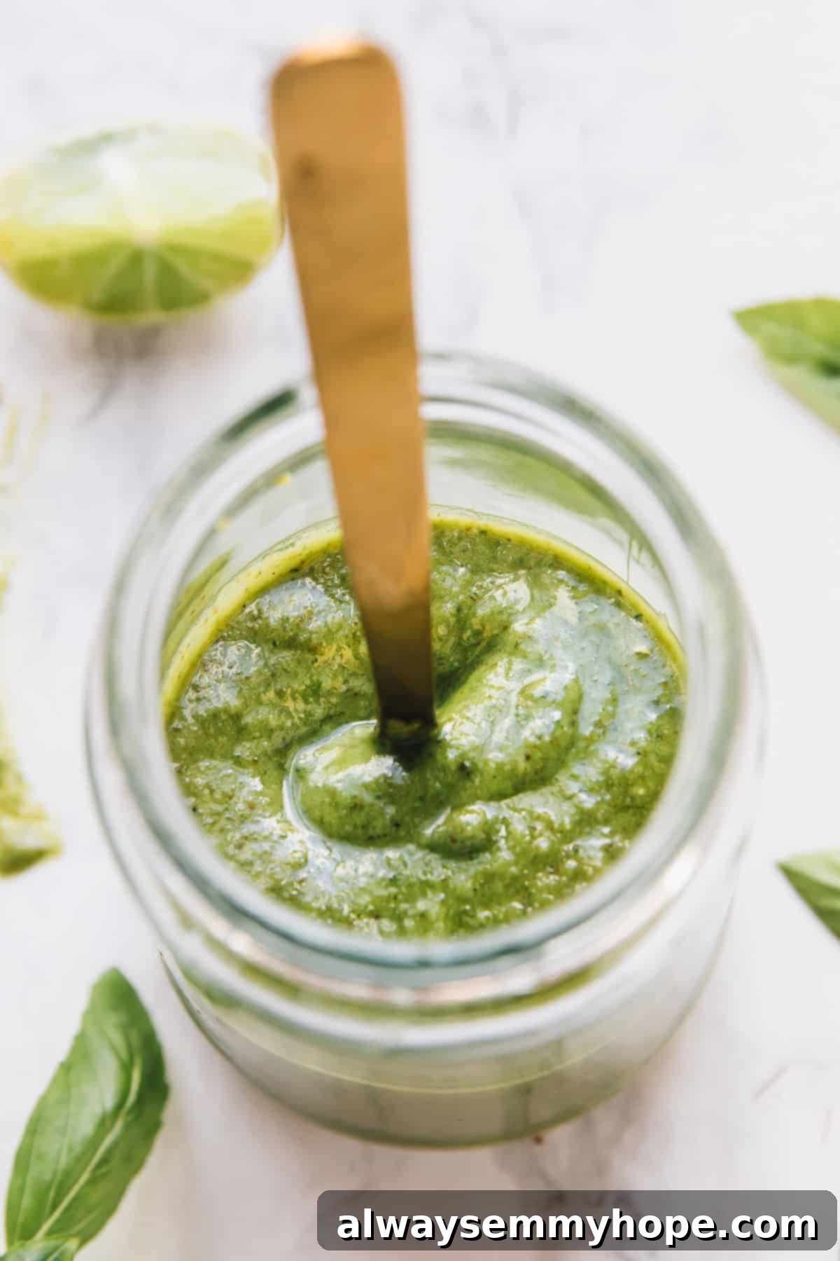 Top down shot of vegan pesto in a glass jar, showcasing its vibrant green color.