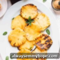 Overhead view of grilled pineapple slices with mint garnish.