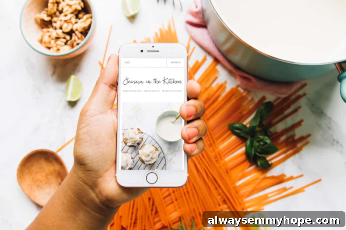 Hand holding a smartphone displaying the mobile version of the Jessica in the Kitchen website, highlighting its responsive and user-friendly design.