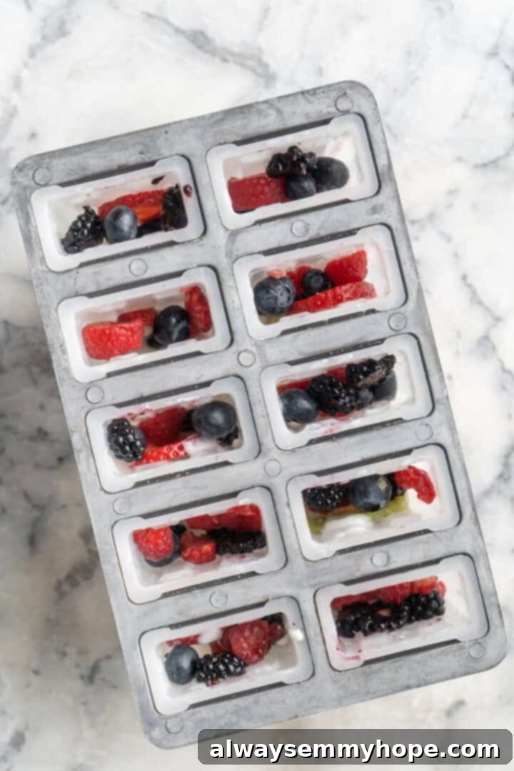 You only need 3 ingredients to make these easy and healthy yogurt popsicles! Enjoy them for breakfast, dessert, or any time in between. Overhead view of fruit in popsicle molds