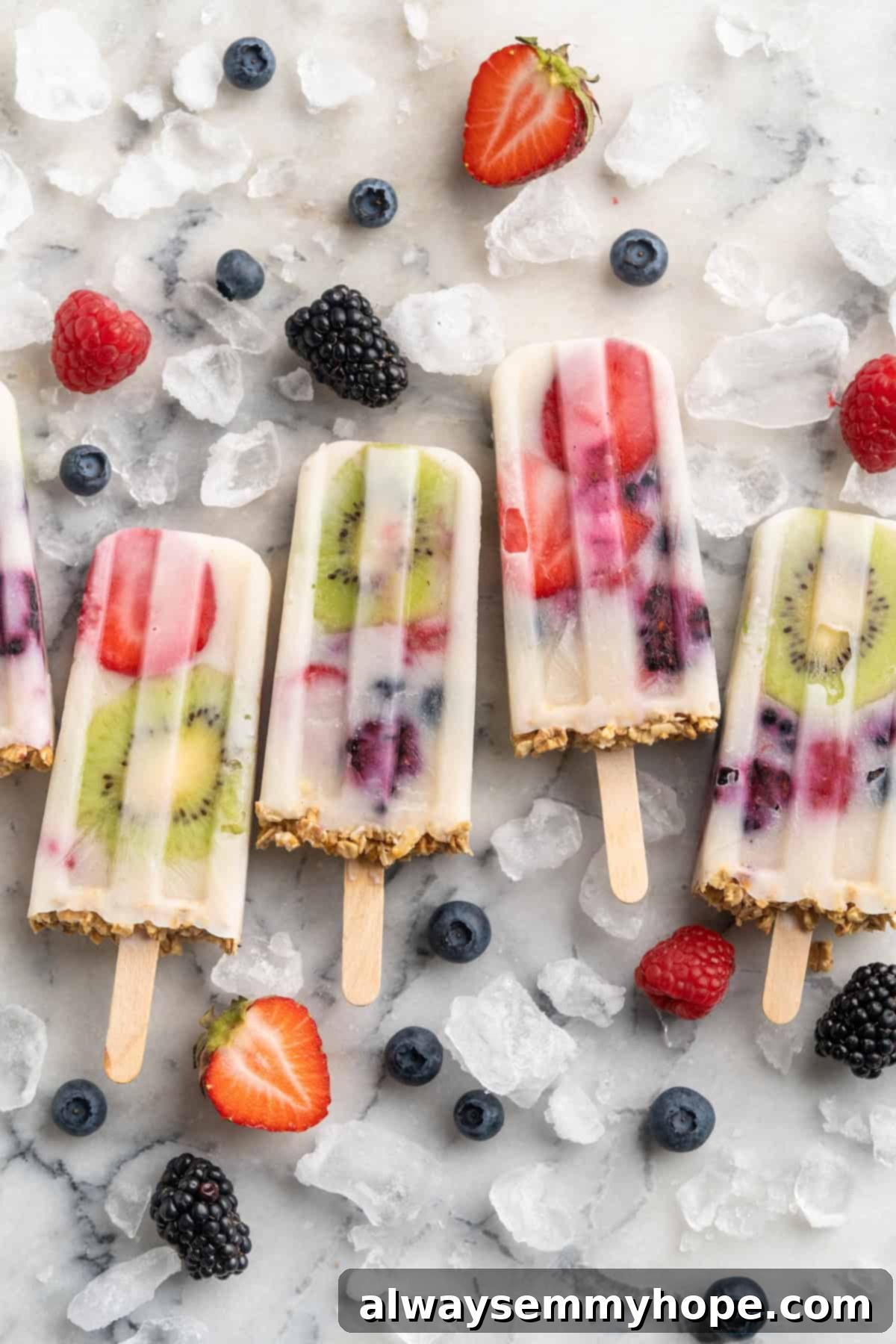 You only need 3 ingredients to make these easy and healthy yogurt popsicles! Enjoy them for breakfast, dessert, or any time in between. Overhead view of yogurt popsicles set on marble slab with ice