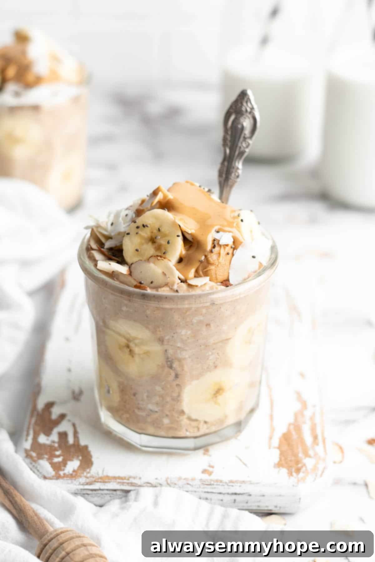 Peanut butter banana overnight oats in jar with spoon, garnished with banana slices and a dollop of peanut butter.