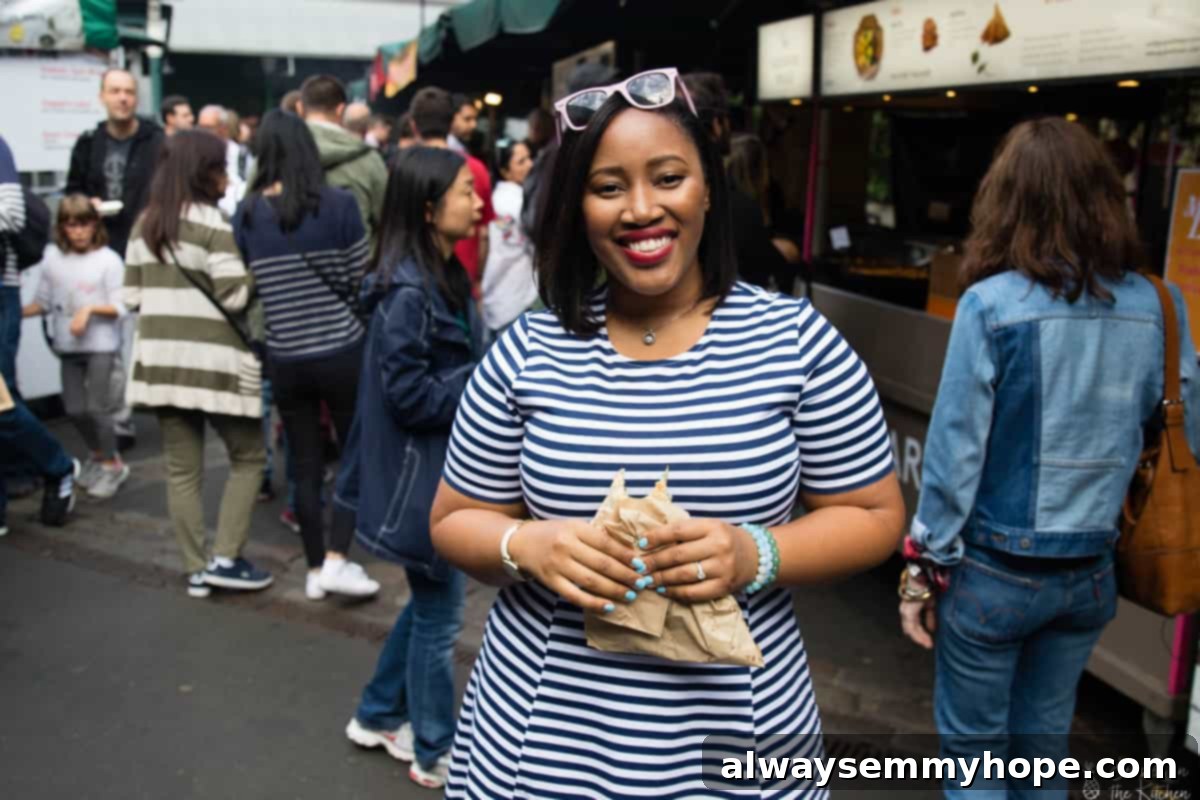Your Essential Guide to London Food and Exploration 12 Jessica in a stylish striped dress, standing amidst the lively atmosphere of Borough Market.