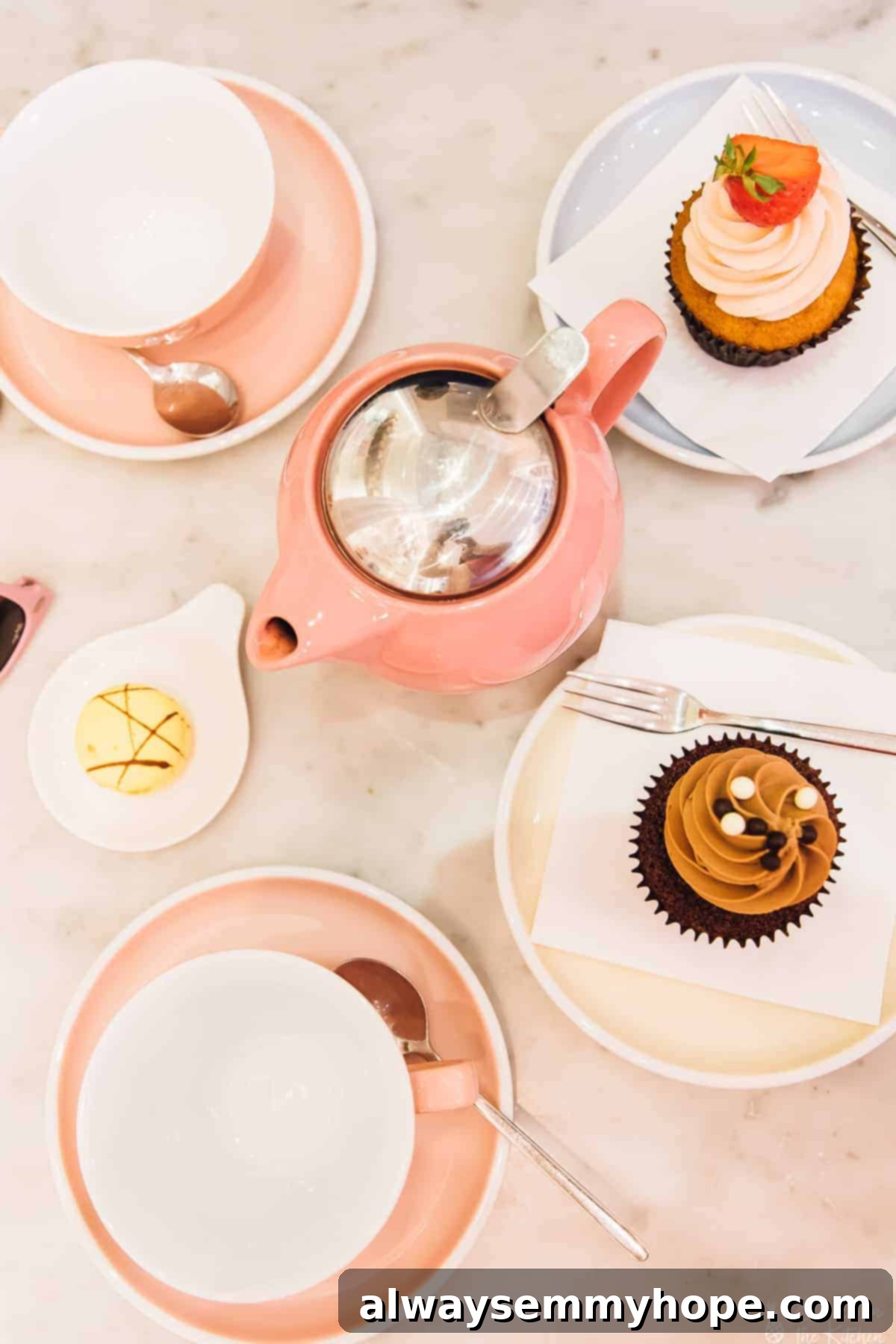 Your Essential Guide to London Food and Exploration 15 Top-down view of charming pink teacups and delectable cupcakes arranged on a table at Peggy Porschen Cakes.