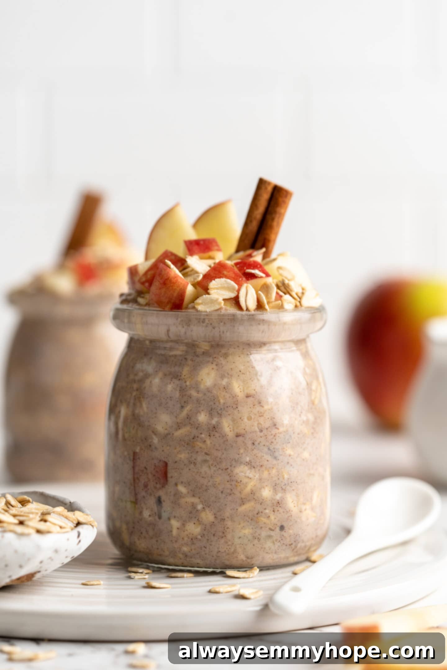 Apple pie overnight oats are packed with crisp apples, warm cinnamon, rich almond milk, and decadent maple syrup, and are an easy breakfast. Two jars of apple pie overnight oats topped with cinnamon sticks, rolled oats, and fresh apple slices, set against a cozy fall backdrop.