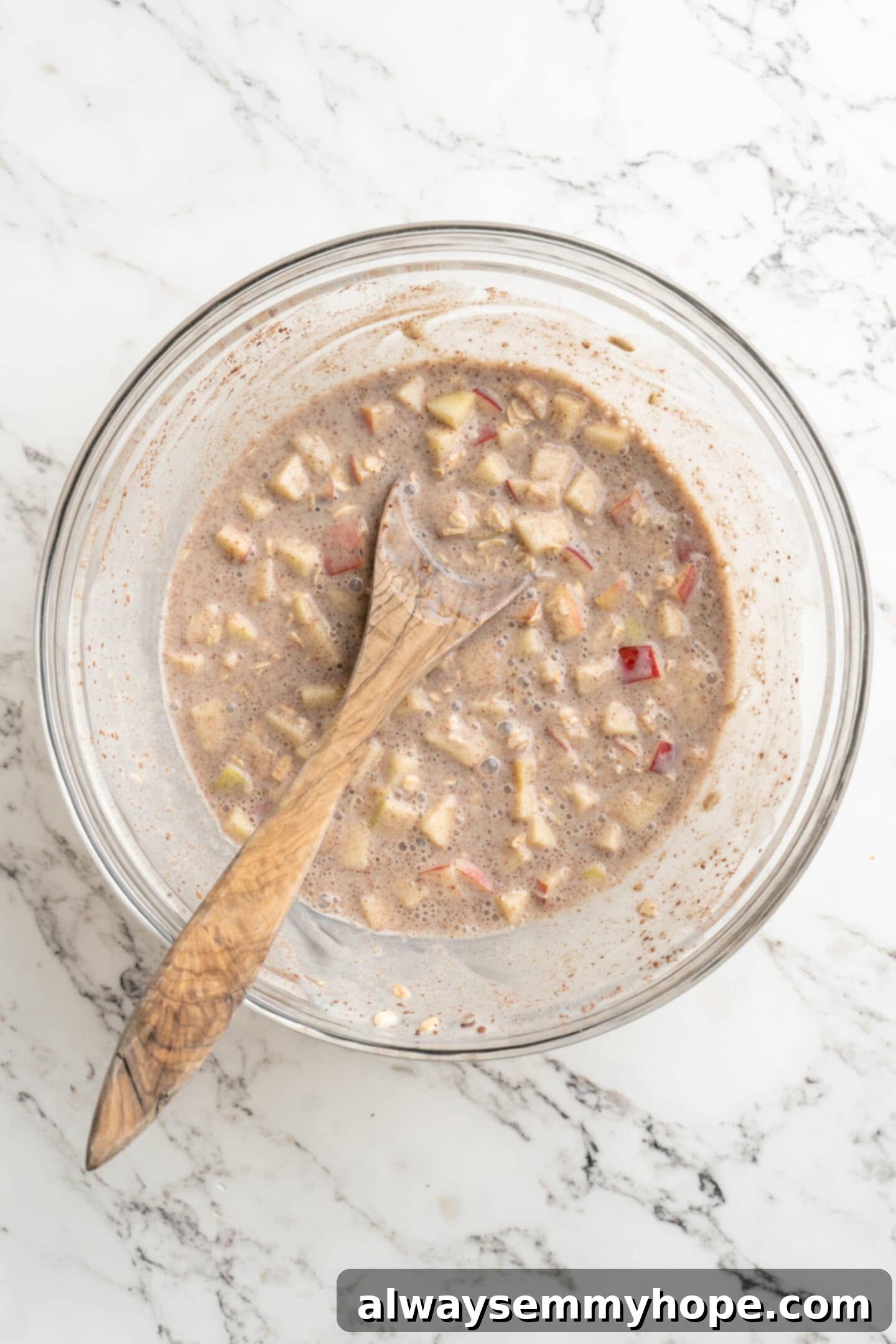 No-Bake Apple Pie Oats 3 Bowl of ingredients for overnight oats mixed together with a wooden spoon, showing the soaked consistency.