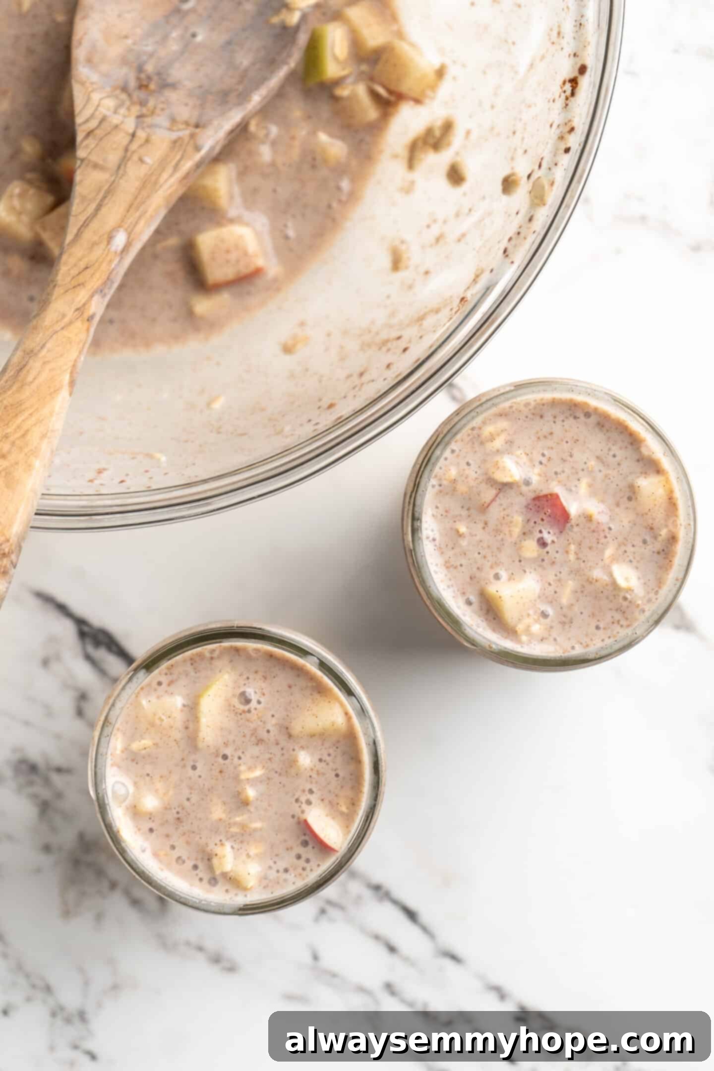 No-Bake Apple Pie Oats 4 Overhead shot of a bowl of prepared overnight oats alongside two jars being filled, illustrating the assembly process.