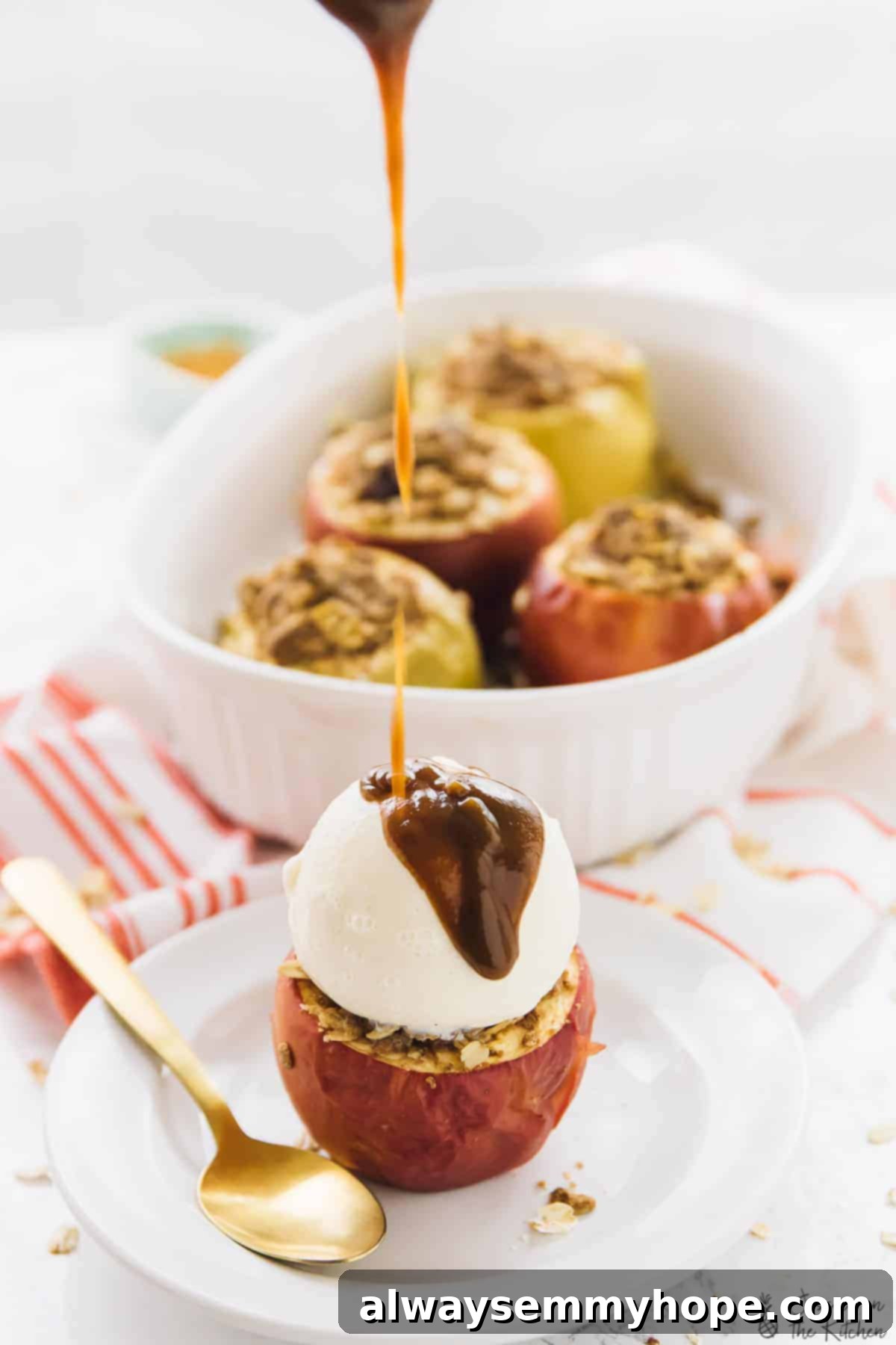 Serve these tender, moist Baked Apples stuffed with crunchy cinnamon oat crisp filling, topped with ice cream and caramel sauce for an unforgettable fall dessert. A baked apple with a generous scoop of vanilla ice cream, artfully drizzled with warm caramel sauce, with more baked apples blurred in the background, hinting at a delightful fall feast.