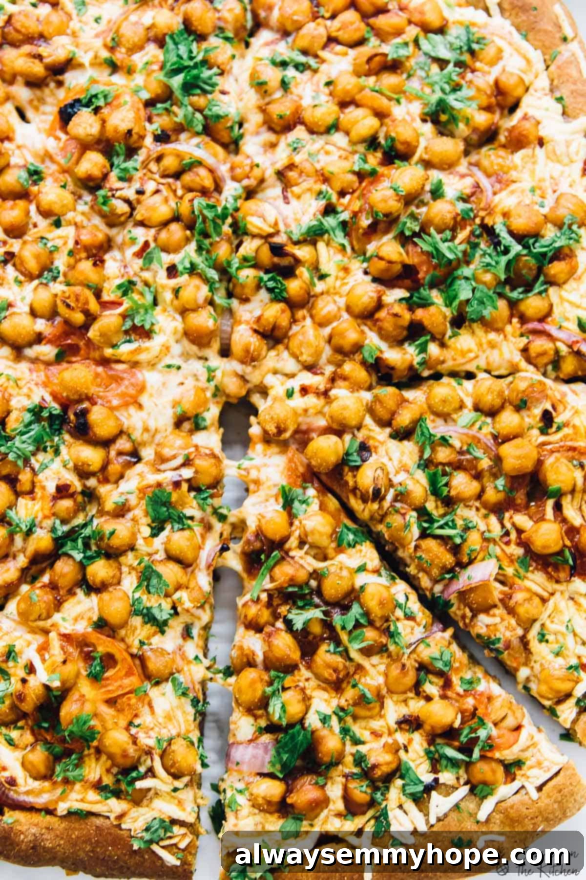 Spicy BBQ chickpea pizza: A delicious vegan alternative to BBQ chicken pizza, packed with flavor and ready in a flash. Close-up overhead shot of a whole spicy BBQ chickpea pizza, with one slice slightly pulled away, showcasing the generous toppings and golden crust.