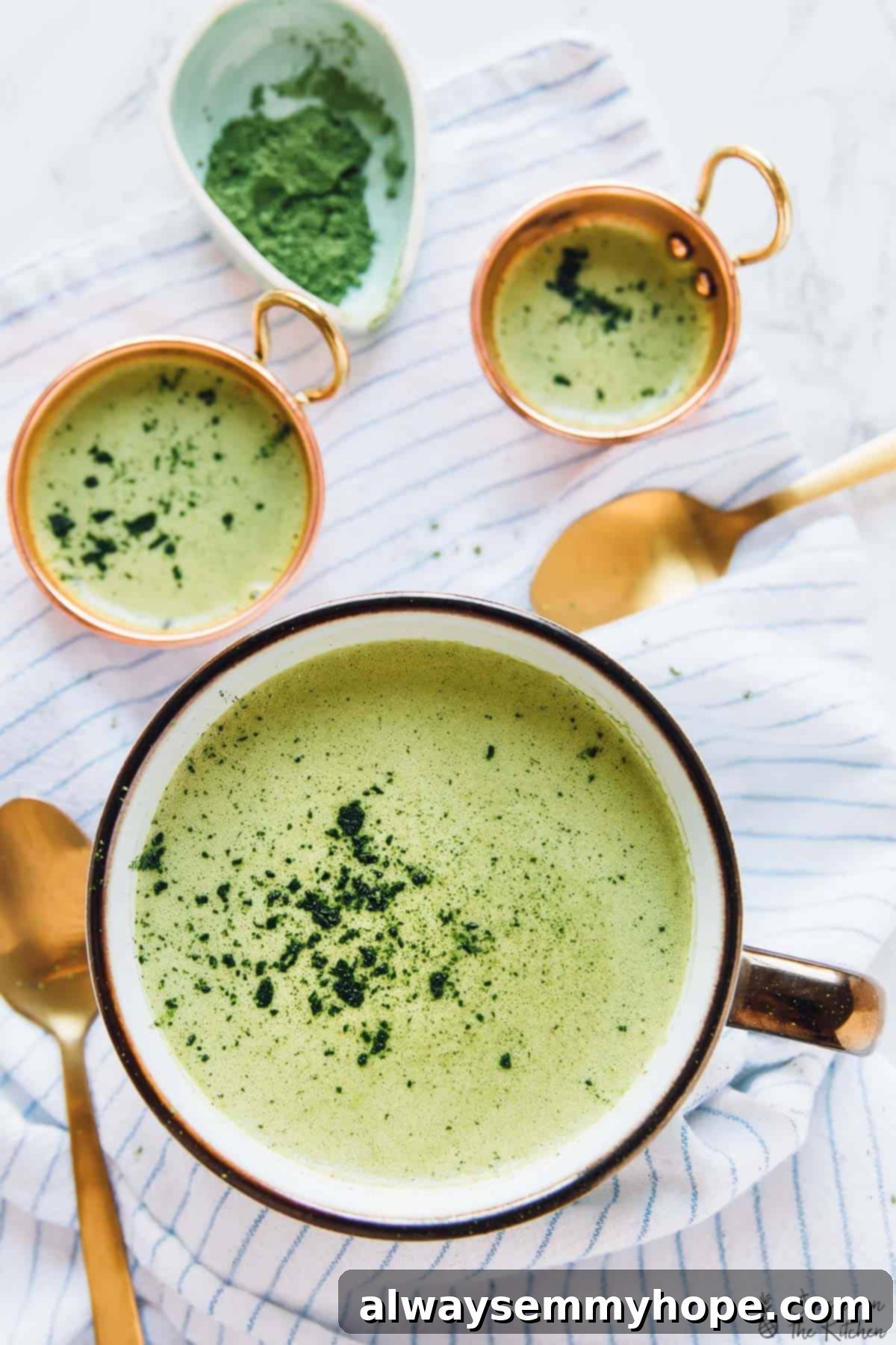 Seasonal Pumpkin Matcha Latte Overhead view of a Pumpkin Spice Matcha Latte in a white cup, placed on a striped fabric, highlighting its frothy texture and festive appeal.