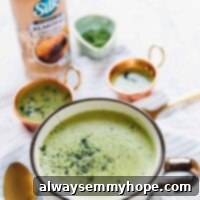 Pumpkin Spice Vegan Matcha Latte 3 A close-up of a creamy matcha latte in a glass, with a bottle of almond creamer in the background, hinting at its delicious ingredients.