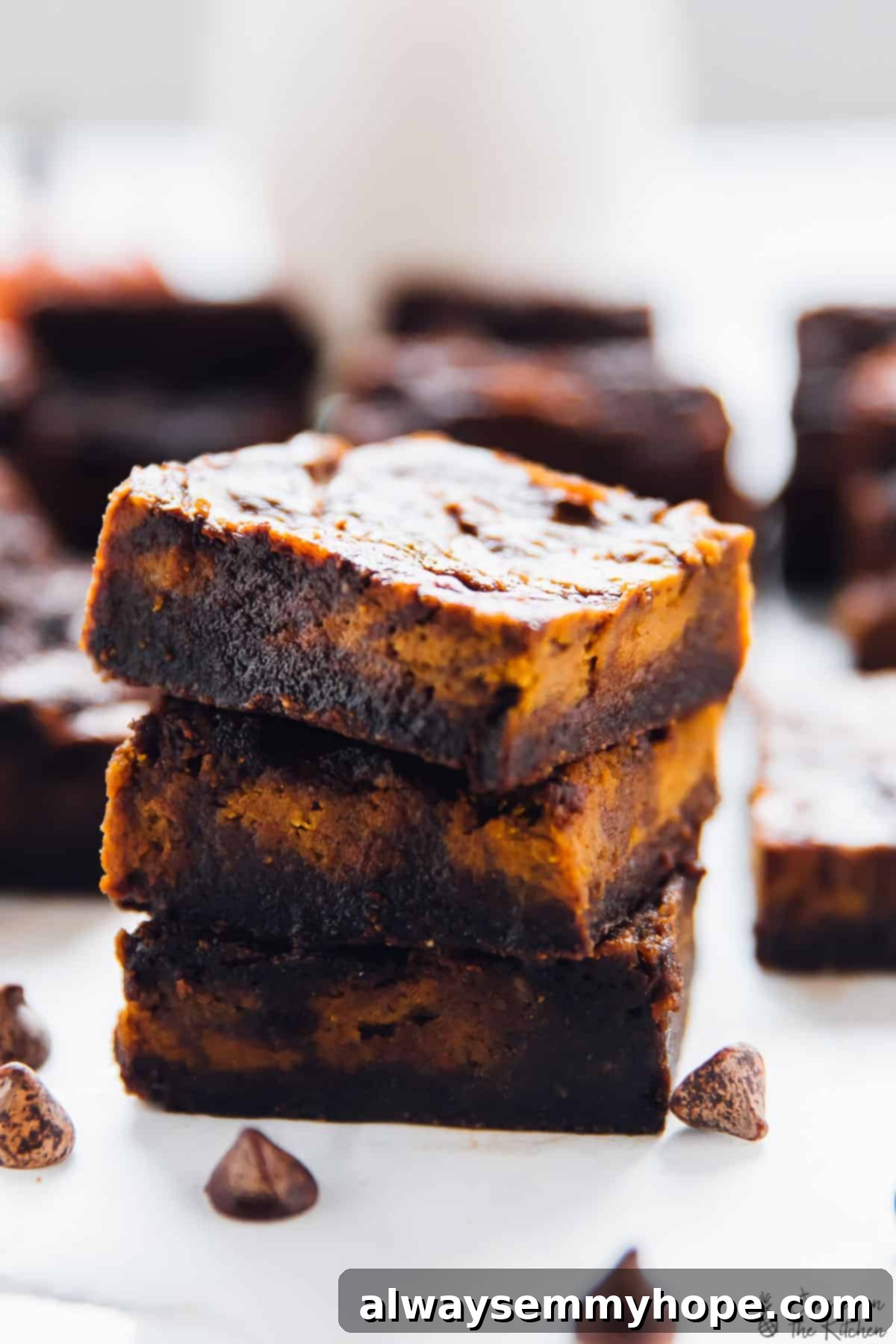 A stack of three squares of brownies with cheesecake swirls, showing the layers and texture.