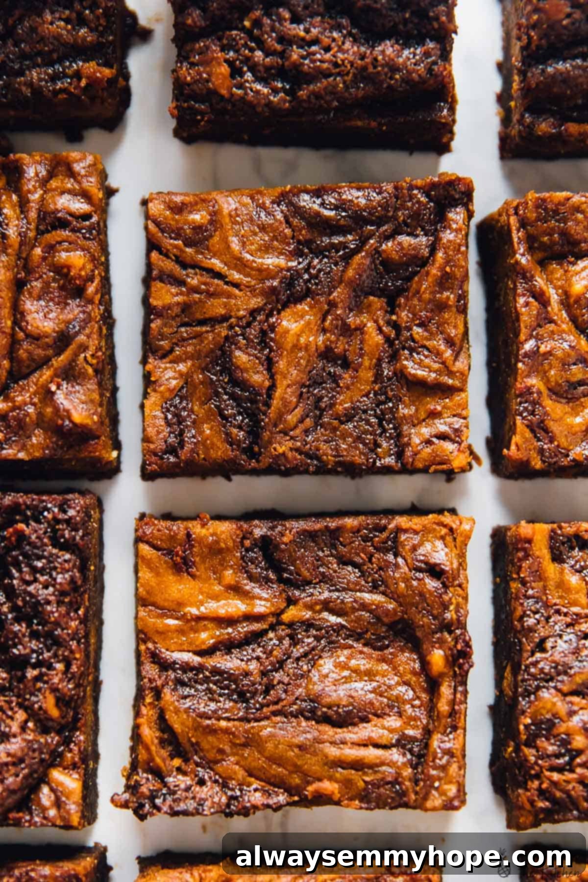Overhead view of a few rows of brownies with cheesecake swirls, perfectly cut and ready to serve.
