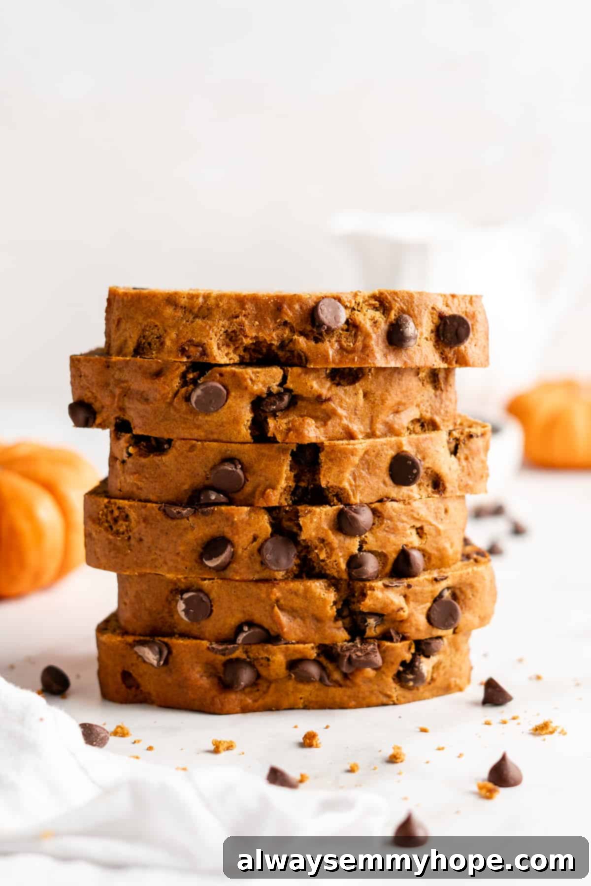 A stack of perfectly sliced vegan chocolate chip pumpkin bread, showing the rich color and abundance of chocolate chips.