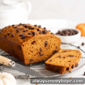 Loaf of pumpkin bread on cooling rack with knife, with one slice cut