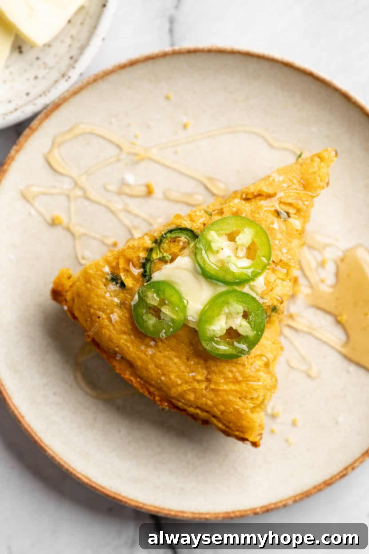 A perfectly sliced piece of golden vegan pumpkin cornbread on a rustic plate, showcasing its fluffy texture and crispy edges.