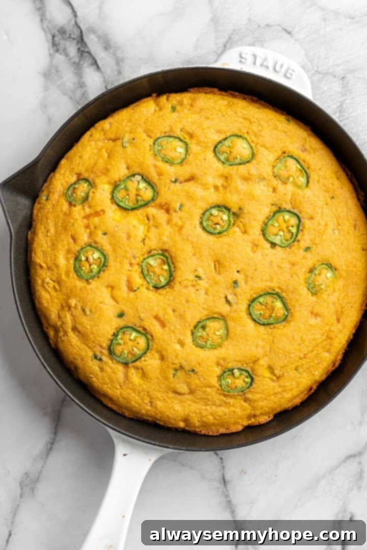 Overhead view of a freshly baked vegan pumpkin cornbread in a cast iron skillet, golden brown and perfectly cooked with crispy edges.