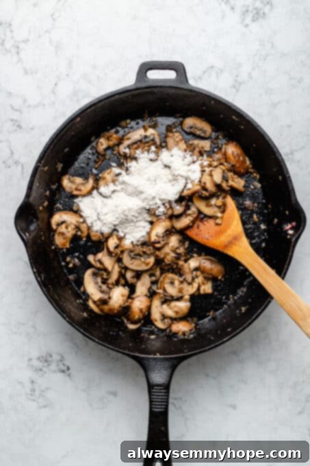 Overhead view of flour sprinkled over mushrooms in skillet