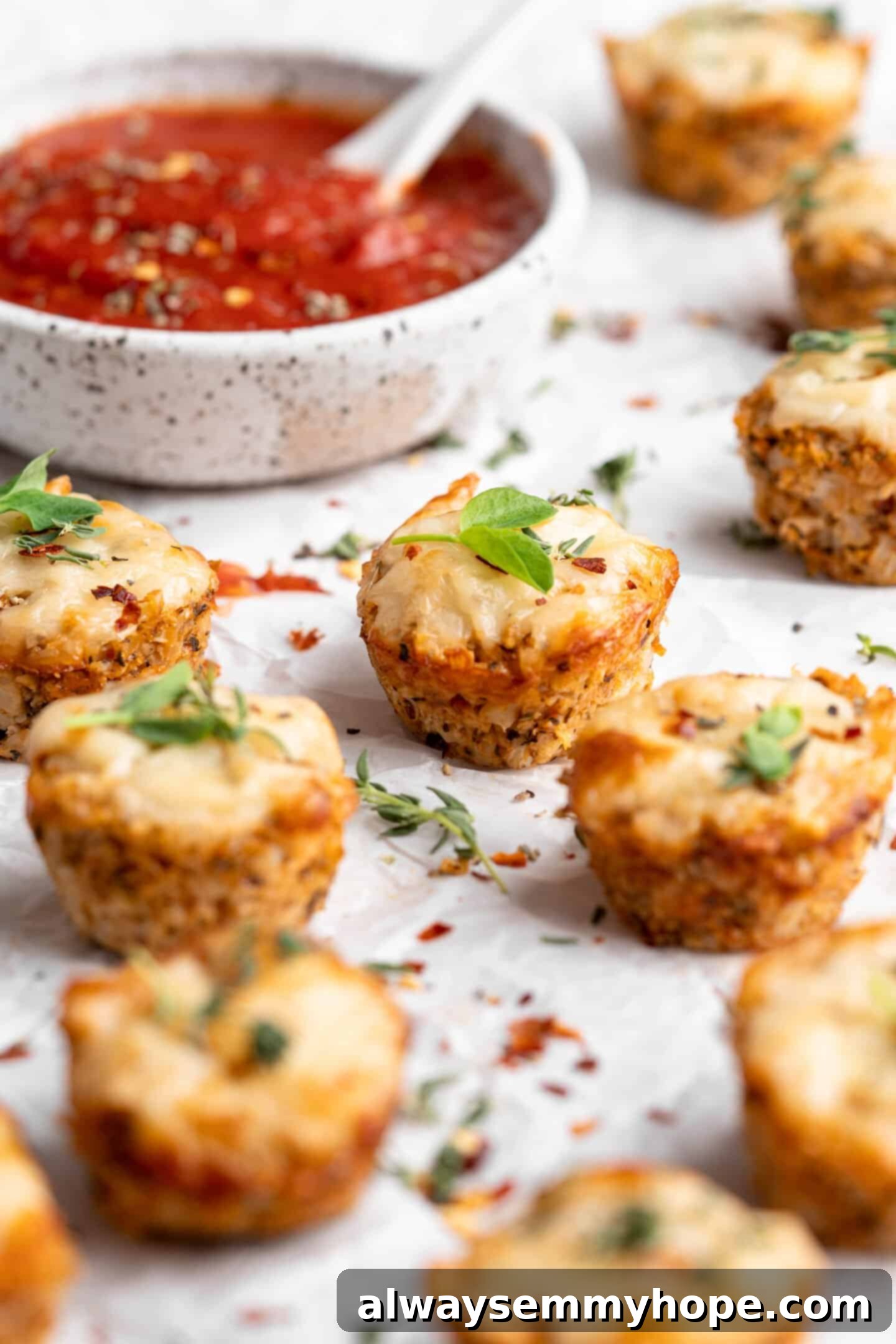 A plate of vegan cauliflower pizza bites in the foreground, with a bowl of marinara sauce blurred in the background, creating a cozy atmosphere.