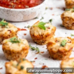 A close-up of delicious vegan cauliflower pizza bites with a bowl of marinara in the background.