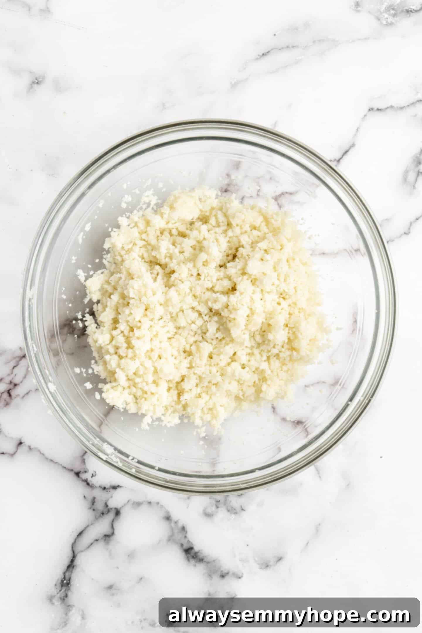 Close-up of fluffy riced cauliflower in a bowl, highlighting its perfect texture after preparation for the pizza bites.