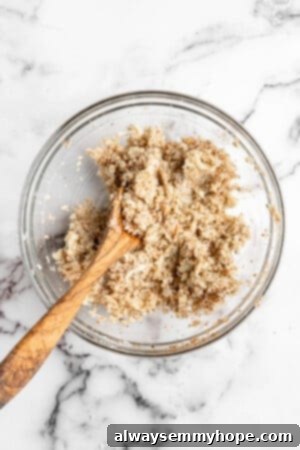 Well-combined cauliflower pizza bite mixture in a clear glass mixing bowl, demonstrating perfect consistency for forming.