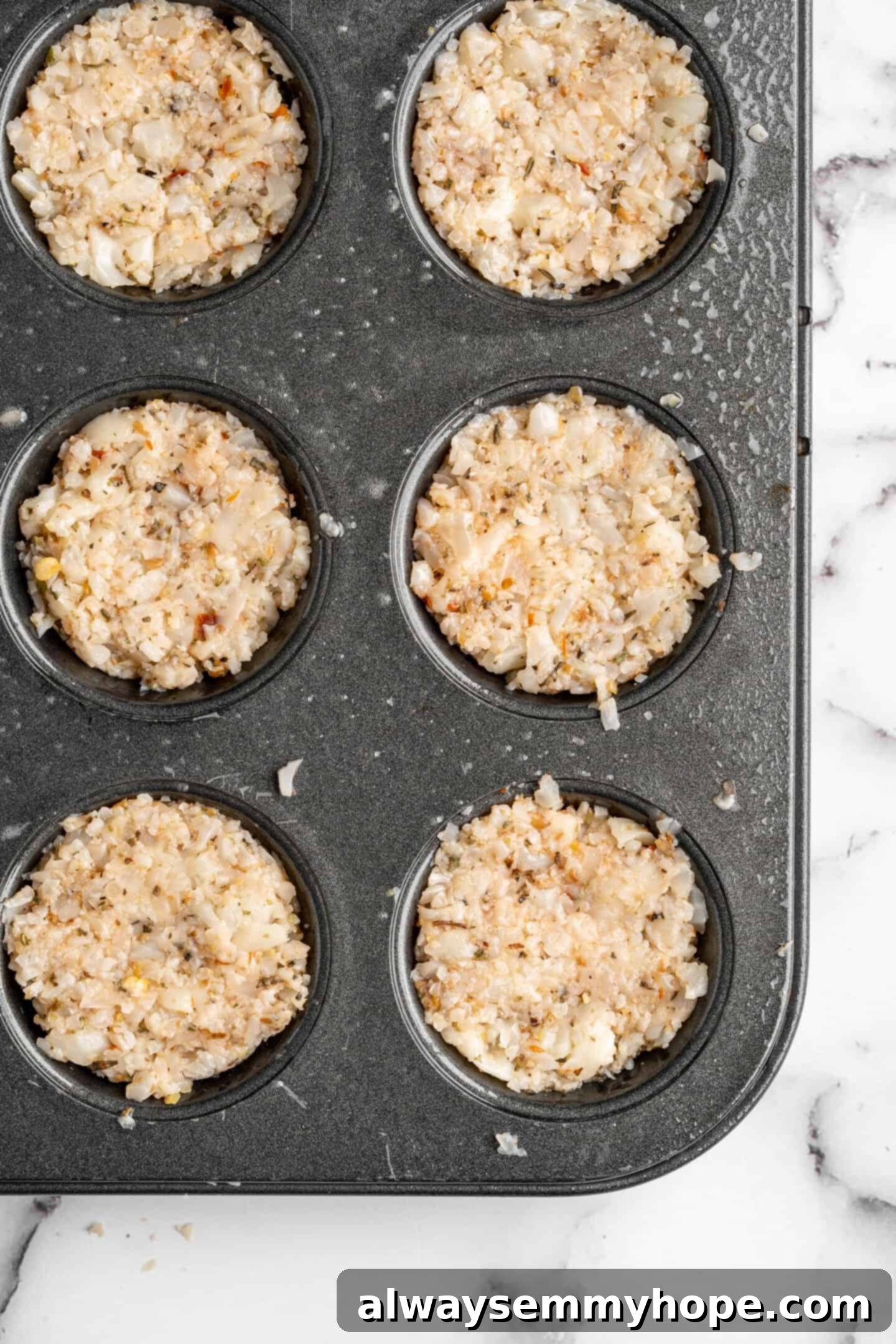 Vegan cauliflower pizza bites neatly arranged in a mini muffin tin before baking, showing the individual portions.