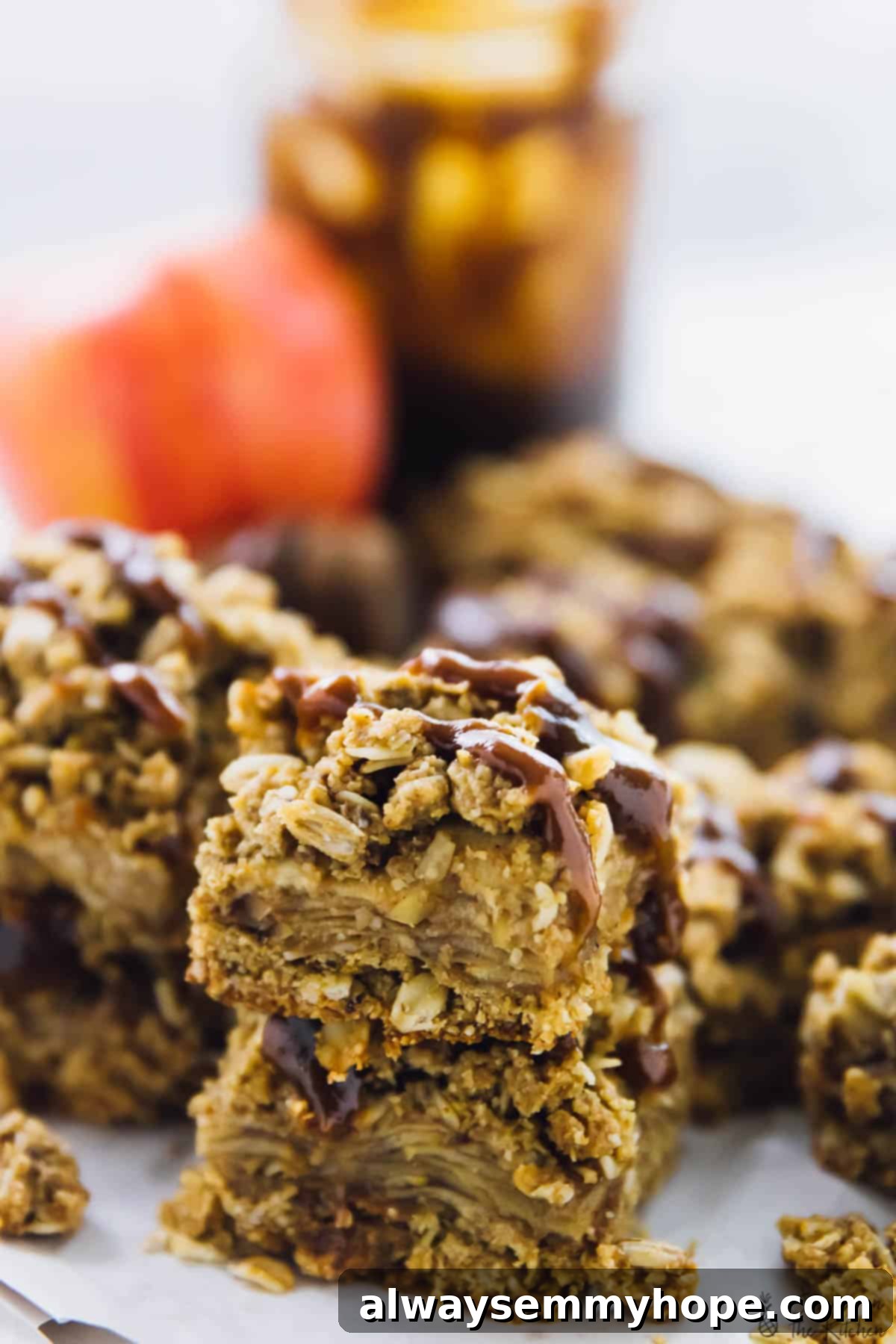 A close up of a batch of vegan apple pie bars with a fresh apple in the background, emphasizing natural ingredients.
