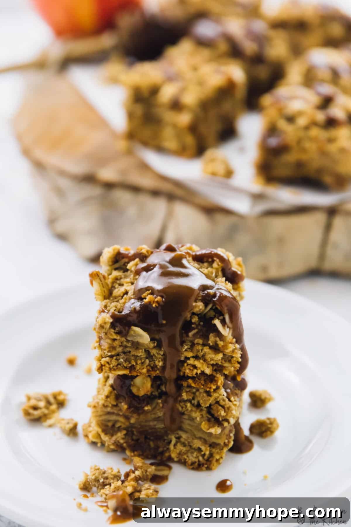 Two perfectly cut vegan apple pie bars, glistening with salted caramel sauce, ready for serving.