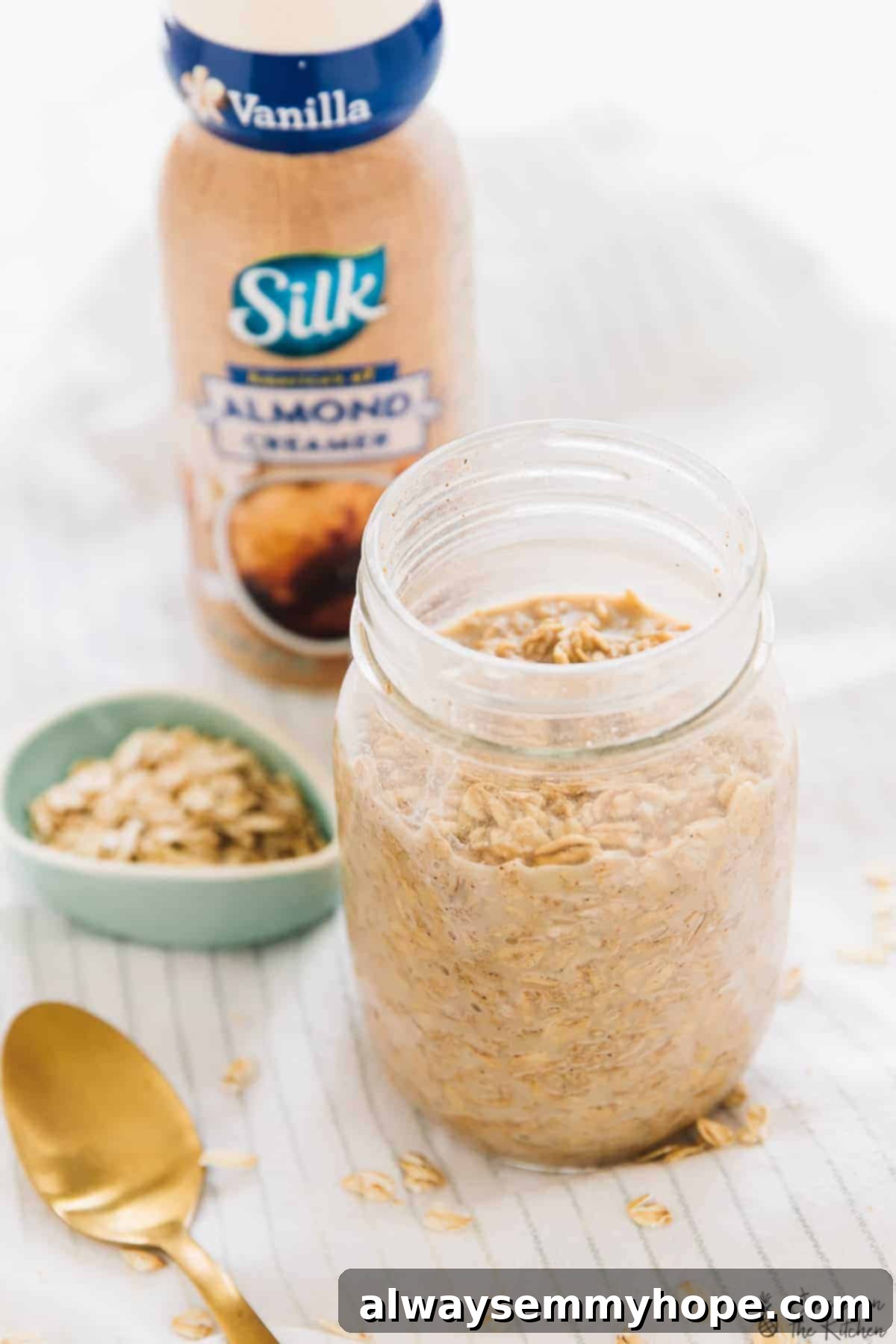 Spiced Espresso Overnight Oats 3 A glass jar filled with Espresso Cinnamon Overnight Oats, with a bottle of almond creamer subtly placed in the soft-focus background, highlighting convenience.